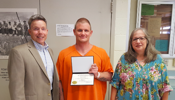 Celebrating his high school diploma is Calvin Combs (center), Gary Sutherland, Principal (left), and Cheryl Urbani, Teacher (right)